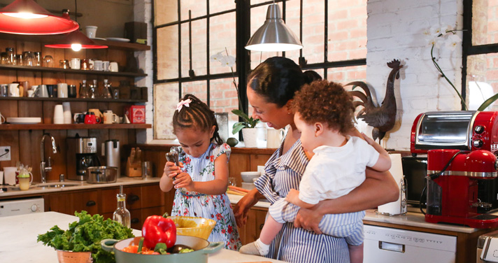 A little girl preparing food with her mother in a kitchen