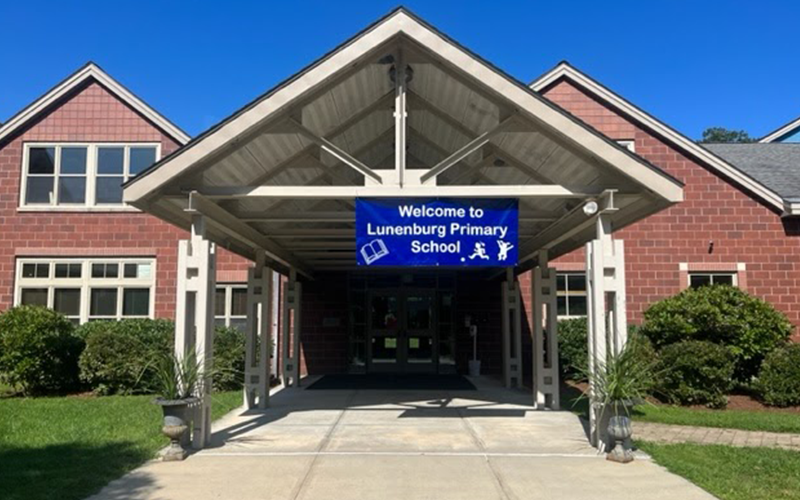 A blue sign on a school says "Welcome to Lunenburg Primary School"