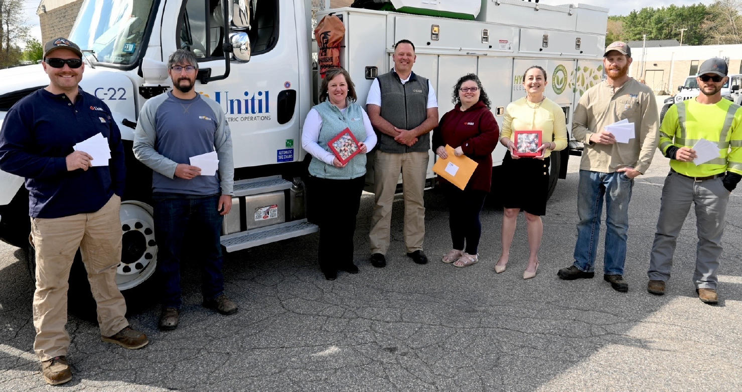 Unitil employees stand in front of a hybrid utility truck