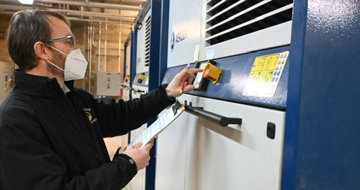 a wastewater plant employee stands with clipboard in front of new machine