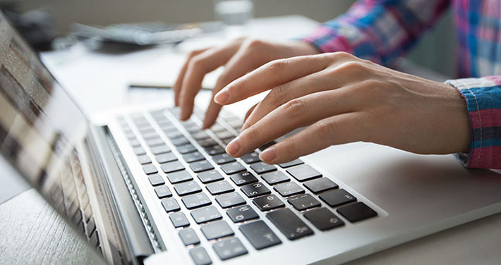 closeup of hands typing on laptop computer