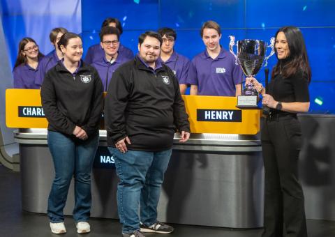 The winning team accepts a trophy in front of the players' podiums