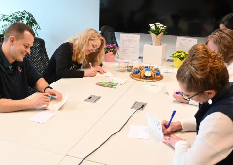 Unitil employees sitting around a table writing greeting cards